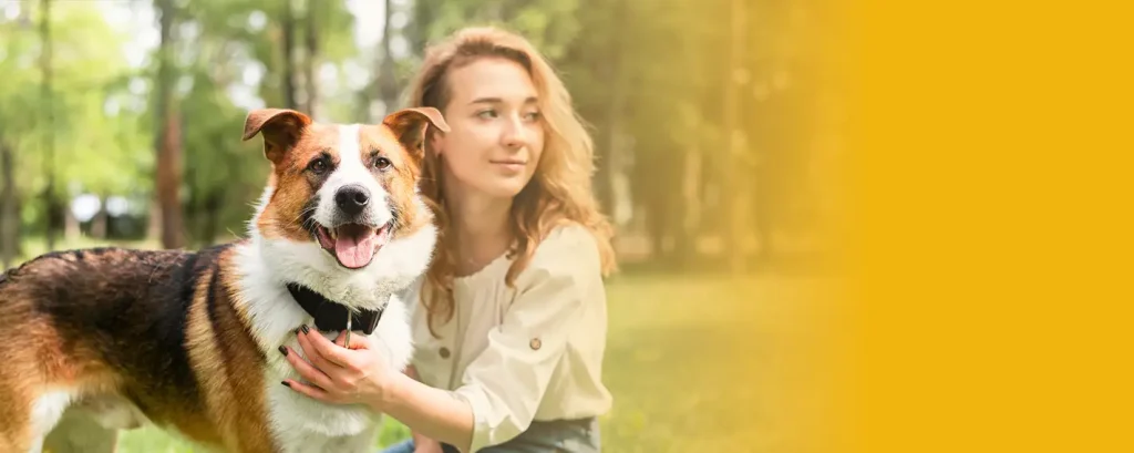 Una chica y su perro en un parque con árboles